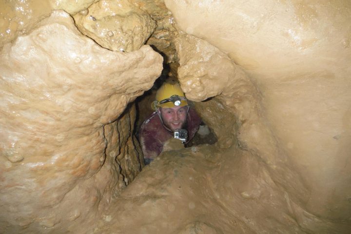 Man Looking up from cavern hole